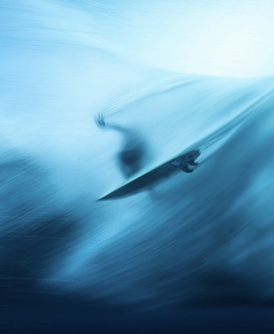 A surfer moving through the barrel of a powerful blue wave