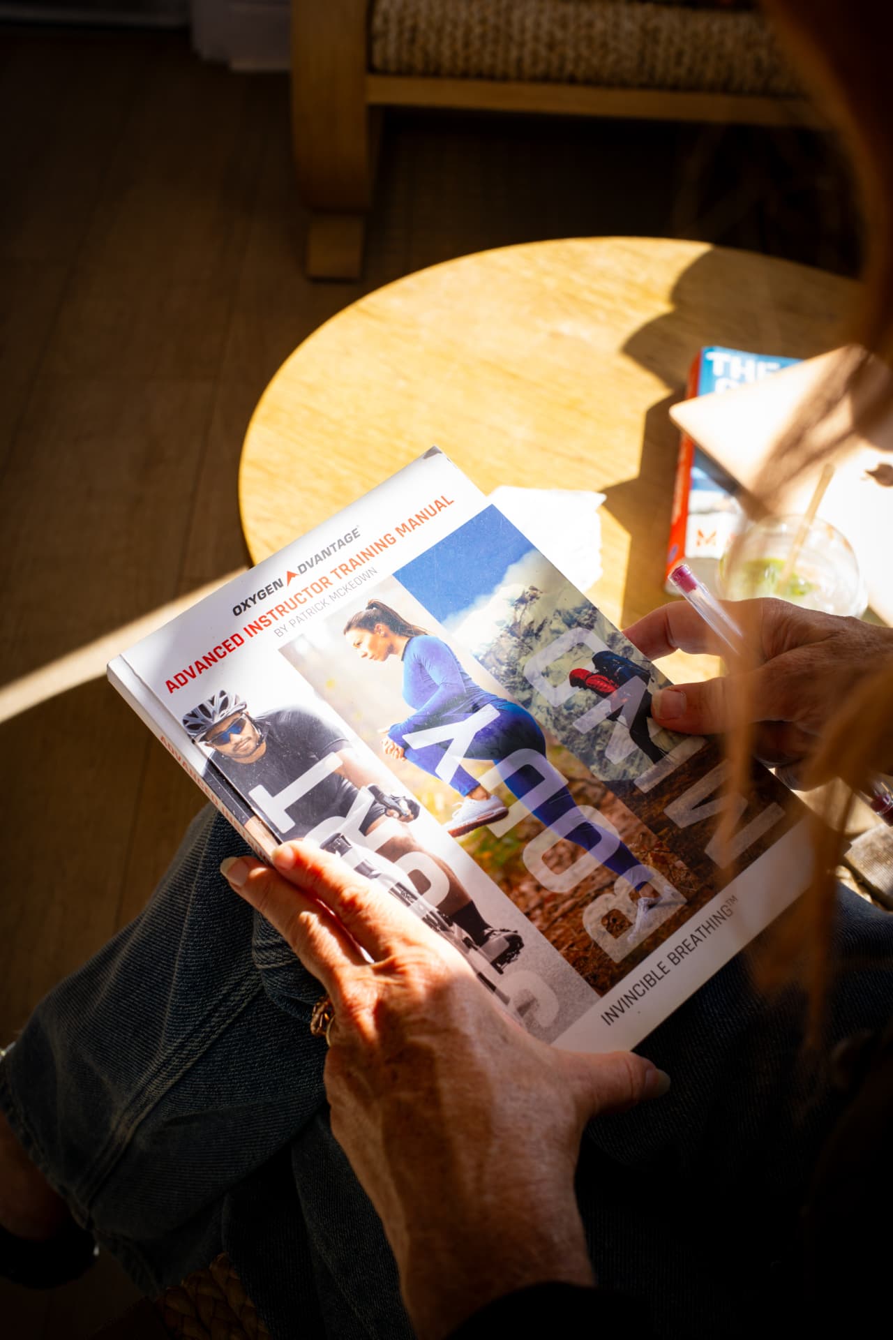 Alix holding an advanced breathing instructor training manual in warm sunlight