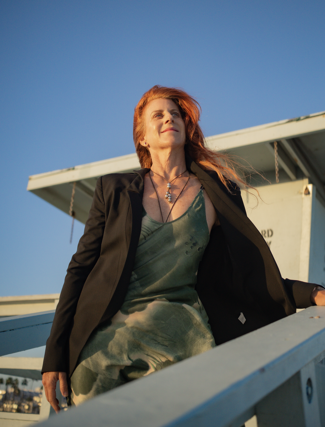 Alix Gucovsky standing on a lifeguard tower, looking up at a clear blue sky